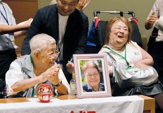 支援者らと喜ぶ鈴木由美さん（前列右）と小林宝二さん（同左）。小林さんの前には妻喜美子さんの写真が置かれた＝東京都千代田区（撮影・堀内達成）