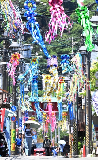 七夕飾りで彩られた商店街で、日傘を差して歩く人たち。地面には「逃げ水」現象も＝４日午前、神戸市須磨区の須磨寺前商店街（撮影・風斗雅博）