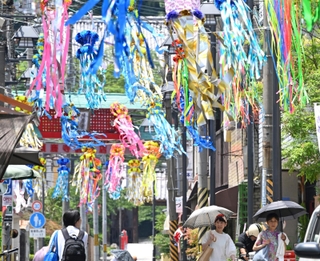 七夕飾りで彩られた商店街で、日傘を差して歩く人たち＝４日午後、神戸市須磨区の須磨寺前商店街（撮影・風斗雅博）