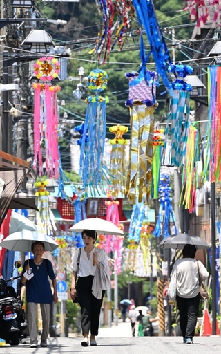 七夕飾りで彩られた商店街を歩く人たち。強い日差しから逃れようと日傘を差す人の姿が多く見られた＝４日午前、神戸市須磨区の須磨寺前商店街（撮影・風斗雅博）