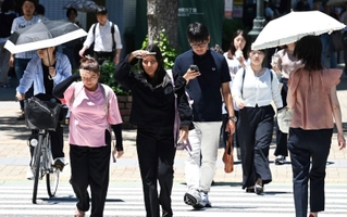 強い日差しに手をかざしたり、日傘を差したりしながら歩く人たち＝５日午後、神戸・三宮（撮影・斎藤雅志）