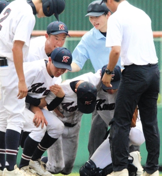 試合中に足をつった選手を支えるチームメートら＝豊岡市戸牧、豊岡こうのとり球場