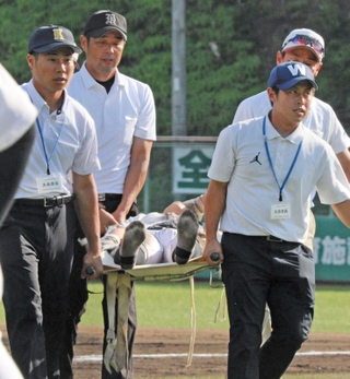 試合中に足をつり、担架で運ばれる選手＝豊岡市戸牧、豊岡こうのとり球場