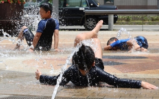 ＪＲ新長田駅前の広場では、子どもたちが水を浴びながら暑さをしのいでいた＝２４日午前、神戸市長田区若松町４（撮影・笠原次郎）