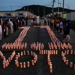 神戸から分灯した火でかたどった「１．１」の文字を囲み、黙とうする人たち＝１日夜、石川県輪島市町野町（撮影・長嶺麻子）