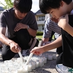 「１・１７希望の灯り」から分灯した火を、「１．１」と形作ったローソクにともしていく地元の子どもら＝１日午後４時４分、石川県輪島市町野町、町野小学校（撮影・長嶺麻子）