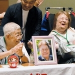 支援者らと喜ぶ鈴木由美さん（前列右）と小林宝二さん（同左）。小林さんの前には妻喜美子さんの写真が置かれた＝東京都千代田区（撮影・堀内達成）