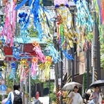 七夕飾りで彩られた商店街で、日傘を差して歩く人たち＝４日午後、神戸市須磨区の須磨寺前商店街（撮影・風斗雅博）