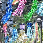 七夕飾りで彩られた商店街で、日傘を差して歩く人たち。地面には「逃げ水」現象も＝４日午前、神戸市須磨区の須磨寺前商店街（撮影・風斗雅博）