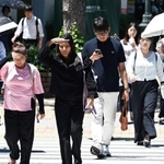 強い日差しに手をかざしたり、日傘を差したりしながら歩く人たち＝５日午後、神戸・三宮（撮影・斎藤雅志）