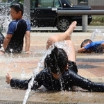 ＪＲ新長田駅前の広場では、子どもたちが水を浴びながら暑さをしのいでいた＝２４日午前、神戸市長田区若松町４（撮影・笠原次郎）