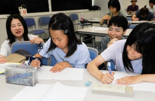 感想文を書く子どもたちを見守る和氣光代さん（左端）と岸本くるみさん（左から３人目）＝神戸新聞社（撮影・杉山雅崇）