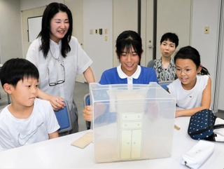 模型を使って子どもたちに家具固定の方法を教える和氣光代さん（左から２人目）と岸本くるみさん（同４人目）＝神戸新聞社（撮影・杉山雅崇）