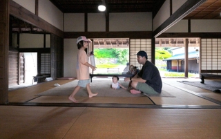 古民家の室内でくつろぐ親子連れ。開放的で天井の高い空間を風が吹き抜ける＝神戸市北区山田町藍那