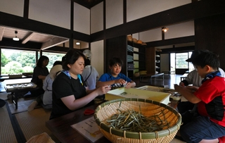 風通しがよい古民家の室内で野草茶作りを体験する親子連れら＝神戸市北区山田町藍那、あいな里山公園