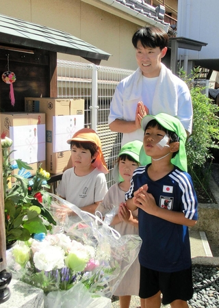 神戸母子寮跡地の地蔵に、訪れた子どもたちと手を合わせる鈴木佑一さん＝２３日午後、神戸市兵庫区湊川町10
