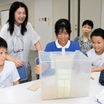 模型を使って子どもたちに家具固定の方法を教える和氣光代さん（左から２人目）と岸本くるみさん（同４人目）＝神戸新聞社（撮影・杉山雅崇）