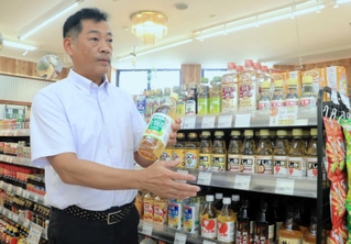 商品の瓶を手に震災時の対応を話す橋本昌俊さん＝マイマルシェ洲本とれたて市場