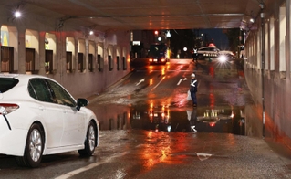 一時冠水したアンダーパスと水没した乗用車（手前）＝１２日午後６時２８分、芦屋市大原町