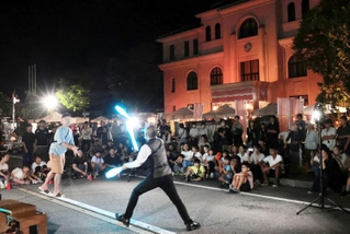 「豊岡演劇祭２０２４」の夜市で、観客も参加して盛り上がった大道芸＝２２日午後、豊岡市中央町