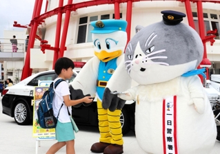 一日署長を務めるデブ猫のマル（右）と兵庫県警のマスコットキャラクターこうへいくん（中央）＝神戸市中央区波止場町