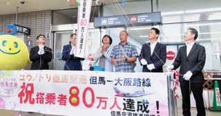 搭乗80万人目となった榎並光治さん（右から３人目）と妻万里子さん（同４人目）＝但馬空港
