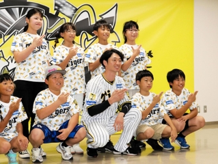 島の形を手でつくる淡路島ポーズを取り、阪神の近本光司選手（前列中央）と記念撮影する児童たち＝西宮市甲子園町、甲子園球場室内練習場