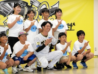 島の形を手でつくる淡路島ポーズを取り、阪神の近本光司選手（前列中央）と記念撮影する児童たち＝西宮市甲子園町、甲子園球場室内練習場