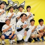 島の形を手でつくる淡路島ポーズを取り、阪神の近本光司選手（前列中央）と記念撮影する児童たち＝西宮市甲子園町、甲子園球場室内練習場