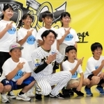 島の形を手でつくる淡路島ポーズを取り、阪神の近本光司選手（前列中央）と記念撮影する児童たち＝西宮市甲子園町、甲子園球場室内練習場