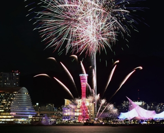 赤くライトアップされた神戸ポートタワーを背景に夜空を彩る花火＝２１日夜、神戸市中央区港島１、ポーアイしおさい公園から（撮影・大田将之）