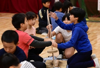 まきストーブで暖を取るため、火をおこす児童たち＝２３日午前、神戸市灘区六甲山町、六甲山小学校（撮影・大田将之）