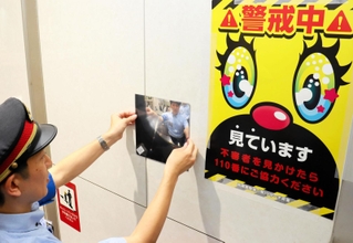エスカレーターに面した壁に盗撮被害防止の広角鏡を設置する駅員＝神戸市中央区のＪＲ三ノ宮駅