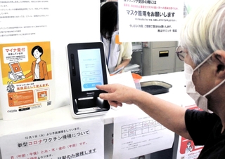 マイナ保険証の読み取り機を操作する女性。「利便性も不安も感じる」＝明石市内