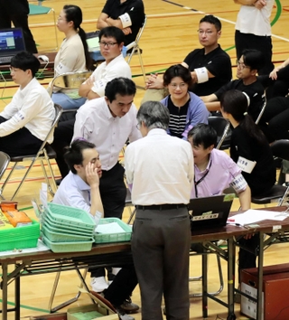 投票者数のデータ誤入力が判明し、確認作業に負われる選管職員ら＝２８日午前２時３９分、伊丹市鴻池１、伊丹スポーツセンター