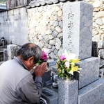 台風23号で亡くなった父孝行さんの墓前で手を合わせる正明さん＝洲本市上内膳