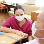 利用者と会話するウクライナ避難民のシュベロバ・オレシアさん＝伊丹市荒牧６、介護老人保健施設「伊丹ゆうあい」