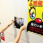 エスカレーターに面した壁に盗撮被害防止の広角鏡を設置する駅員＝神戸市中央区のＪＲ三ノ宮駅