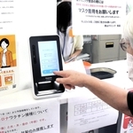 マイナ保険証の読み取り機を操作する女性。「利便性も不安も感じる」＝明石市内
