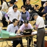 投票者数のデータ誤入力が判明し、確認作業に負われる選管職員ら＝２８日午前２時４１分、伊丹市鴻池１、伊丹スポーツセンター