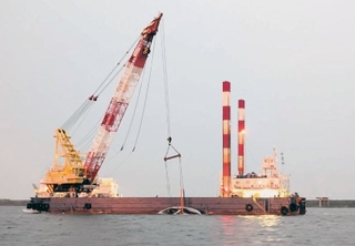 台風21号の接近に伴い、海上からクジラの死骸を陸揚げするクレーン船（神戸市提供）