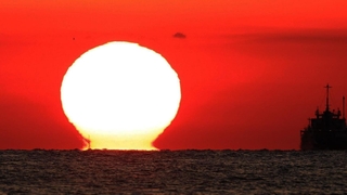 空を赤く染めながら水平線に沈んでいく「だるま夕日」＝１１日夕、神戸市垂水区から播磨灘を望む