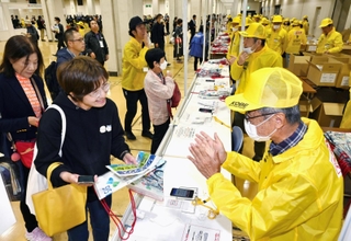 受け付けでアスリートビブスなどを受け取る神戸マラソンの出場者ら＝１５日午後、神戸市中央区港島中町６、神戸国際展示場（撮影・斎藤雅志）