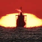 水平線に沈んでいく夕日と船が重なった＝神戸市垂水区西舞子１から播磨灘を望む