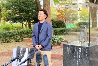 来年の「つどい」に設置する灯籠の数を減らす方針などを示す実行委員長の藤本真一さん＝神戸市中央区、東遊園地
