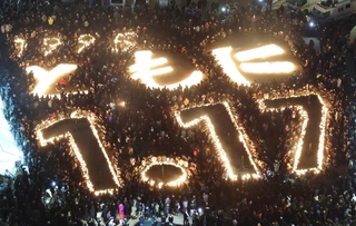ろうそくの明かりで浮かび上がった「ともに　１・１７」の文字＝１月１７日午前５時４６分、神戸市中央区加納町６、東遊園地