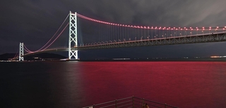 ヴィッセル神戸の２冠を祝って、ライトアップされた明石海峡大橋。海面もチームカラーに染まった＝１３日夜、神戸市垂水区海岸通から（撮影・風斗雅博）