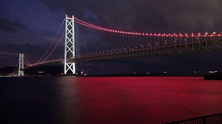 ヴィッセル神戸の２冠を祝って、ライトアップされた明石海峡大橋。海面もチームカラーに染まった＝１３日夜、神戸市垂水区海岸通から（撮影・風斗雅博）
