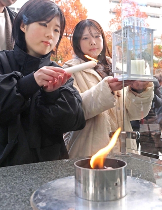 「１・１７希望の灯り」を分灯する黒田愛実さん（左）と西出梨乃さん＝神戸市中央区加納町６（撮影・笠原次郎）