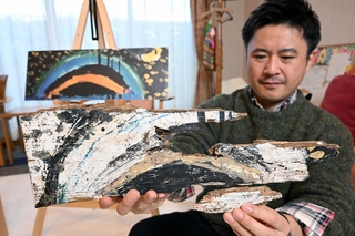 レインボーハウスに届けられた「黒い虹」の絵の一部を持つ職員。左奥は制作当時を再現したレプリカ＝２４日午前、神戸市東灘区本庄町１（撮影・風斗雅博）